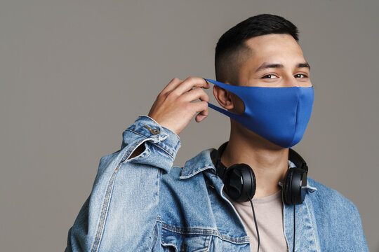 Brunette happy man in face mask posing with headphones