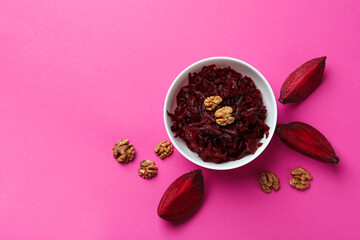 Fresh beet salad and walnut on pink background, top view