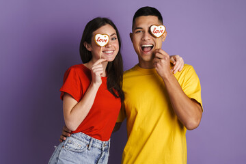 Brunette happy couple smiling while posing with heart biscuits