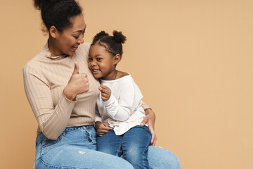 Happy black mother and daughter hugging and showing thumb up