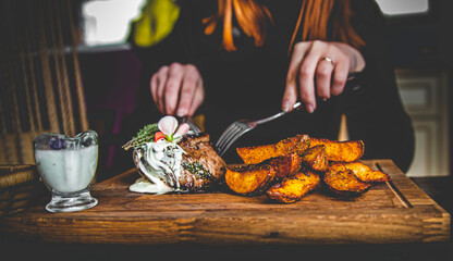 woman hands with fork and knife eating beef steak in cafe