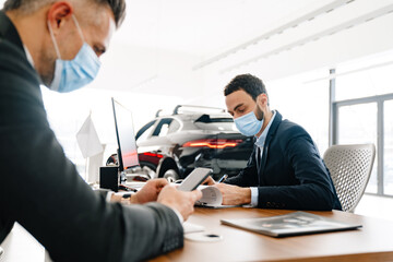 Mid unshaven manager working with mature customer in car showroom