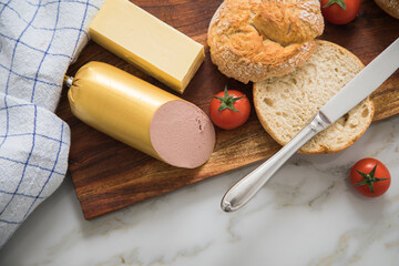 Feine Kalbsleberwurst mit zwei Weizen Rosen Brötchen, Tomaten, Butter und Messer auf Holzbrett,...