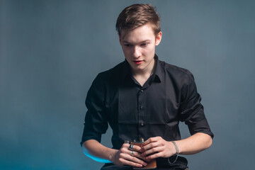 A young man sits on a bar stool and drinks alcohol from a flask