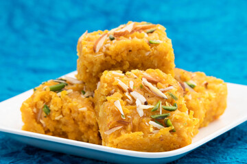 Sindhi Indian Mithai Sev Badam Halwa Burfi Barfee Or Barfi Is Made Of Bengal Gram Flour Besan Kaju Kesar Pista Khoya Meetha Doodh Mawa Malai In Desi Ghee. Isolated On Blue Background With Copy Space