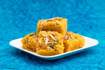 Sindhi Indian Mithai Sev Badam Halwa Burfi Barfee Or Barfi Is Made Of Bengal Gram Flour Besan Kaju Kesar Pista Khoya Meetha Doodh Mawa Malai In Desi Ghee. Isolated On Blue Background With Copy Space