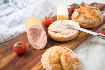 Feine Kalbsleberwurst auf Weizen Rosen Brötchen dazu Tomaten, Butter mit Holzbrett, Geschirrtuch...