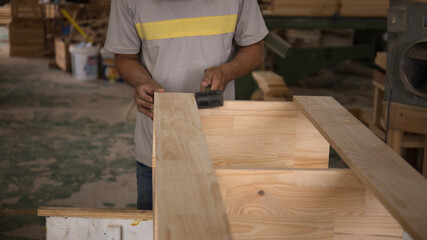 Close-up of hand carpenter joining wood planks at an angle. Man working in workshop. Joinery work on the production and renovation of wooden furniture. Small Business Concept