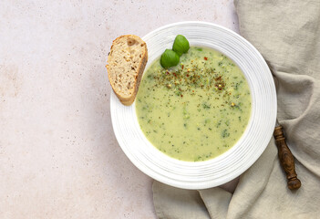 Broccoli cream soup served with cream and fresh bread on light marble table. Healthy vegetarian food concept.