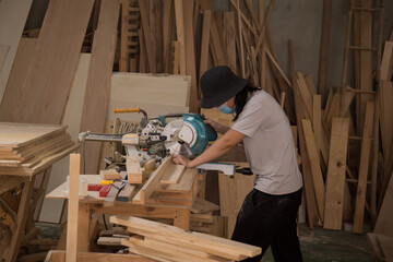 Carpenter working on wood with electric circular saw in workshop. Joinery work on the production of wooden furniture. Small Business Concept