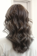 Obraz premium light brown long curly loose hair closeup photo in hair salon back view