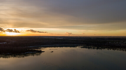 Aerial view of a beautiful and dramatic sunset over a forest lake reflected in the water, landscape drone shot. Blakheide, Beerse, Belgium. High quality photo