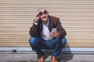 adult man squatting using mobile phone in the city