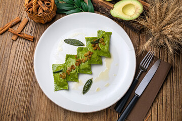 Green dumplings with spinach and sauce on a large white plate
