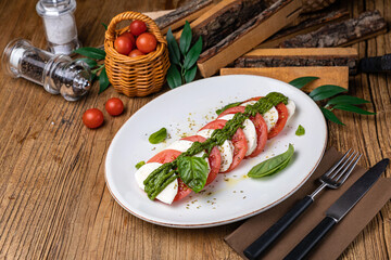 Mozzarella, tomatoes, basil sauce on a white plate
