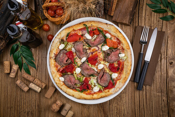 Pizza with tomatoes, meat, soft cheese and herbs
