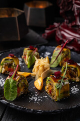 Japanese rolls on a dark plate in a restaurant
