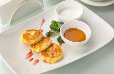 Cheesecakes with sour cream and honey on a white table
