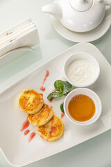Cheesecakes with sour cream and honey on a white table

