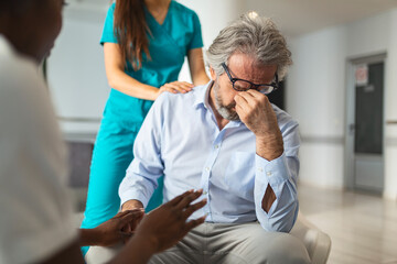 Obraz premium Female doctor reassuring supporting senior adult patient in hospital. Kind caring young woman nurse or caregiver helping older retired man talking, giving comfort, expressing care concept.