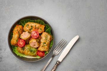 Golubtsi or golabki in black bowl on concrete table top. Stuffed cabbage rolls dish of russian, polish, ukrainian cuisine. European food. Copy space