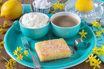 Zitronen-Schmand-Kuchen mit Schlagsahne und Tasse Kaffee