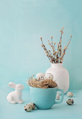 easter eggs and willow branches in bird nest on blue background