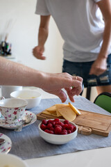 Obraz na płótnie Canvas family early breakfast in a white kitchen with cheese with tea and berries a man's hand takes cheese