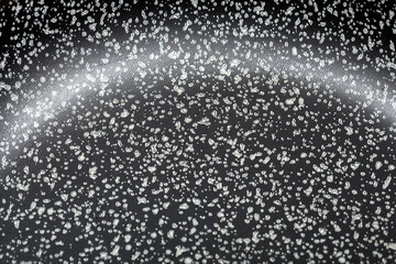 bottom of the pan made of fluoroplastic coating of dark color with dots closeup, texture of the coating of cookware.