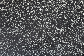 clean surface of a frying pan with a non-stick coating of dark color with a speck close-up, the texture of the coating of kitchen utensils.