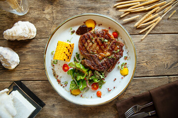 Grilled beef steak with corn on the wooden background
