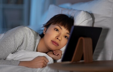 asian woman with tablet pc in bed at home at night