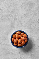 Hazelnuts in a bowl viewed from above on a grey background. Top view. Copy space