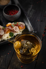Cocktail with ice and cherry on a dark table. Snacks for a cocktail
