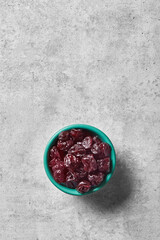 Sour cherry in a bowl viewed from above on a grey background. Top view. Copy space