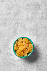 Candied pineapple in a bowl viewed from above on a grey background. Top view. Copy space