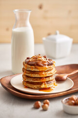 Sweet pancake breakfast with milk and hazelnuts on a wooden utensils and wooden background