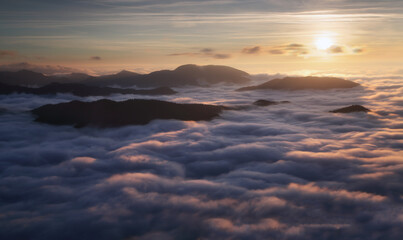 Fototapeta premium Sunset hidden behind clouds and fog over hills, bright yellow sun on colorful cloudscape, blue violet orange sky.