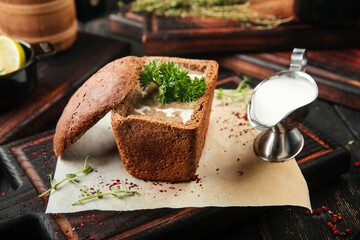 Gourmet mushroom cream soup in a bread with sauce and parsley