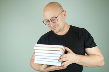 man with glasses with a stack of books in his hands, the concept of knowledge. a young professor with books in his hands.