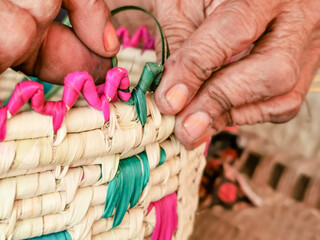 an old working woman and making handcraft by dried palm tree leaves