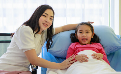 Cheerful girl with mother on sofa in hospital room