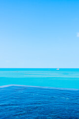 Obraz premium Beautiful private infinity outdoor swimming pool with sea ocean white cloud and blue sky view