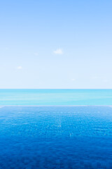 Obraz premium Beautiful private infinity outdoor swimming pool with sea ocean white cloud and blue sky view