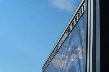 Abstract business background. Glass windows of an office building against the blue sky with space...