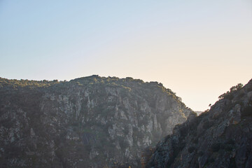 Three rocky mountains with cliffs at sunset.
