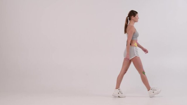 female athlete with kinesiotape on her body runing from left to right