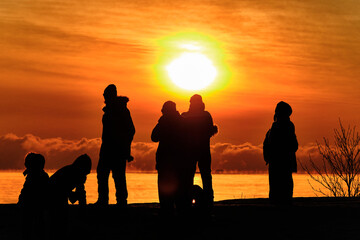 Fototapeta premium Silhouettes of people on the background of an orange sunset over the sea