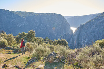 Sunset view of rocky, winding, steep mountains and a river reflecting sunlight