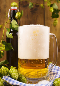 Beer. Pint of Beer close up on a wooden background. Cold Craft light Beer in a glass with water drops. Beer is pouring from the bottle. Border design. Copy space. High quality photo